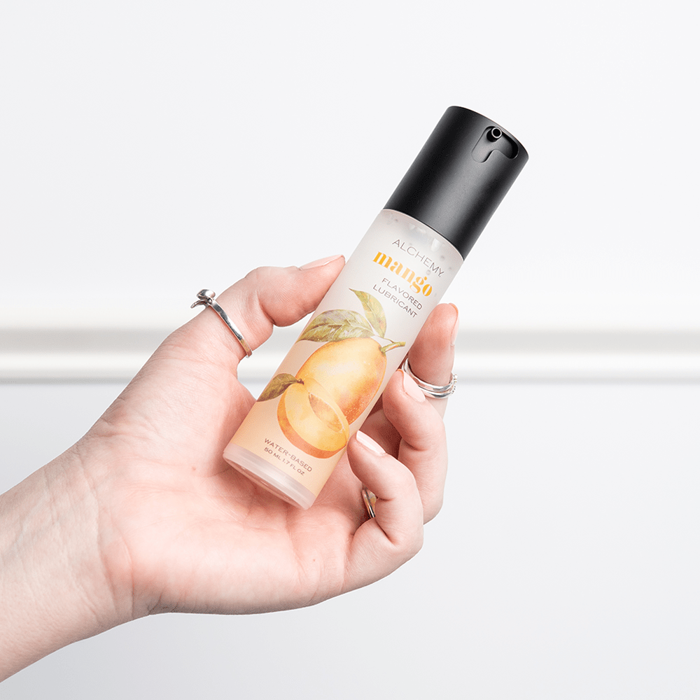 Alchemy Indulge: Mango Flavored Personal Lubricant bottle in woman's hand