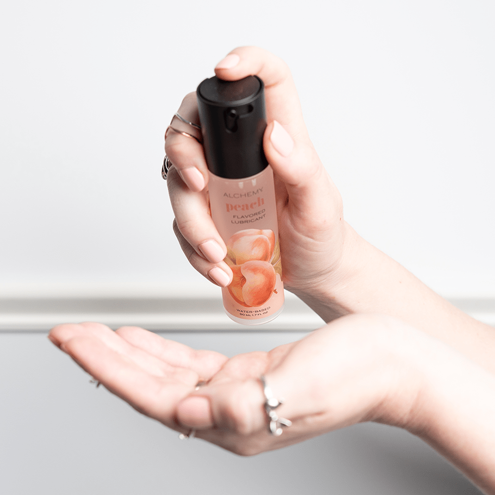 Alchemy Indulge: Peach Flavored Personal Lubricant bottle in woman's hands