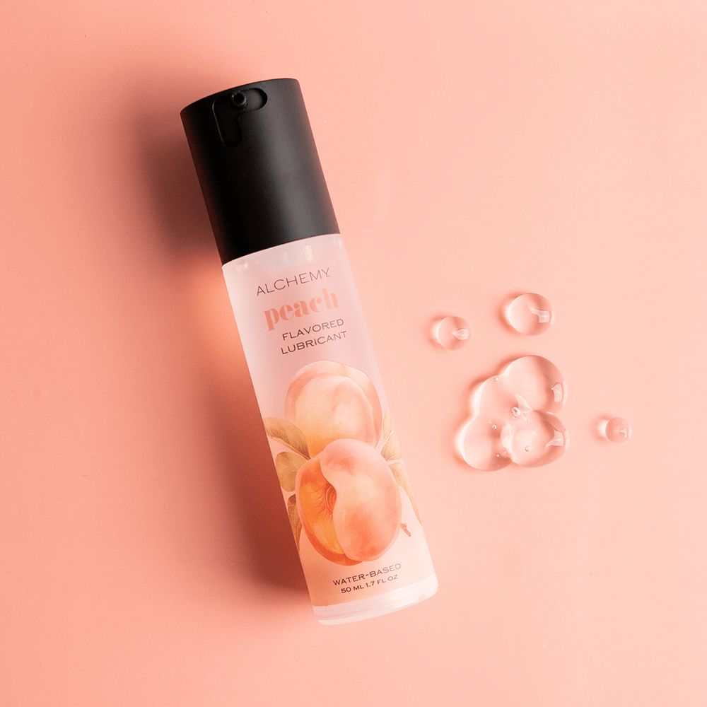 Alchemy Indulge: Peach Flavored Personal Lubricant bottle with liquid droplets