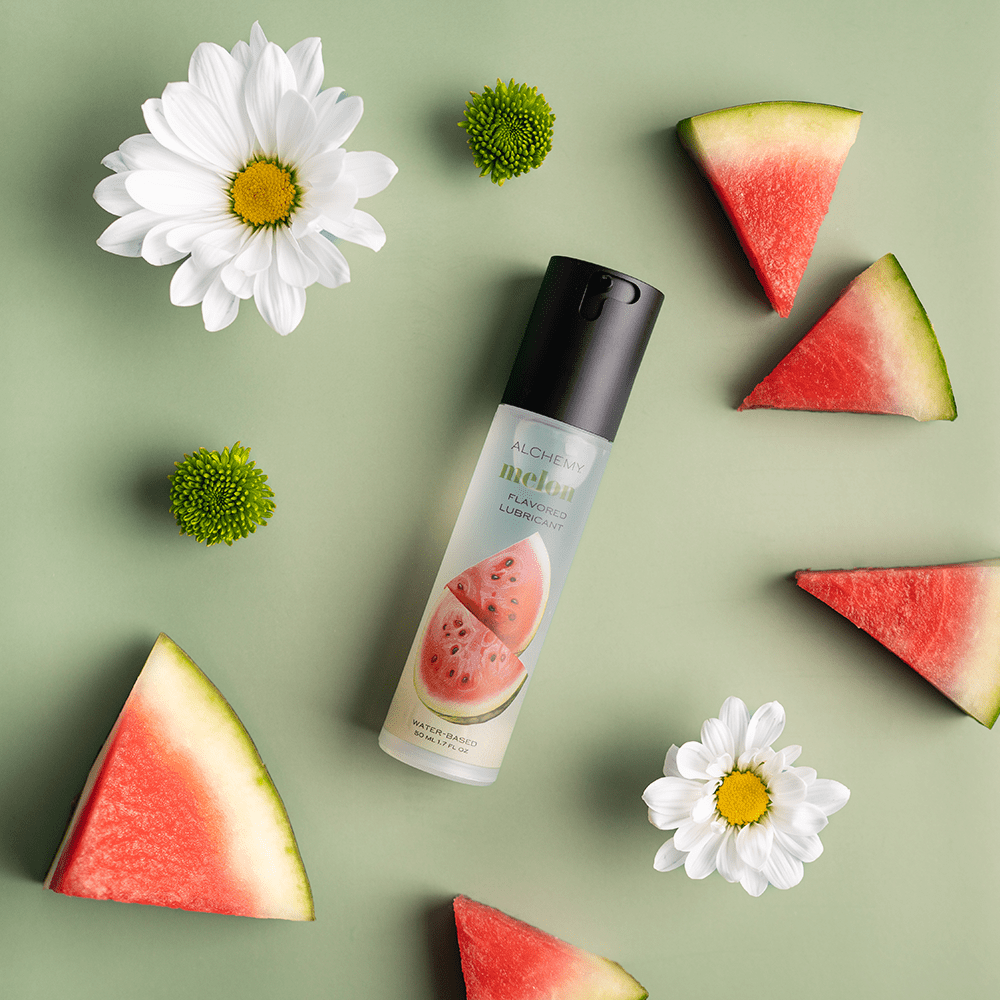 Alchemy Indulge: Watermelon Flavored Personal Lubricant bottle with watermelon slices and flowers
