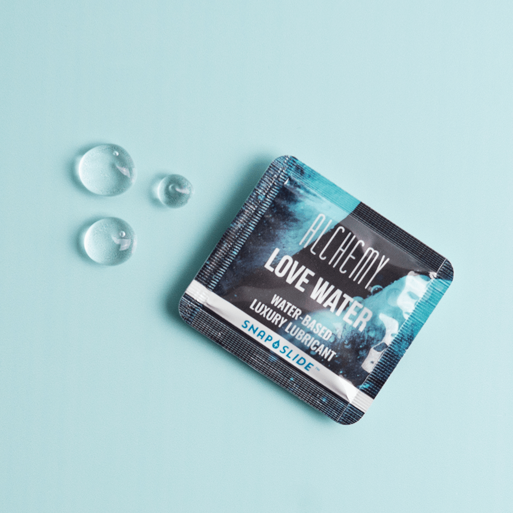 Alchemy Love Water Water-Based Snap + Slide Single-Use Personal Lubricant Packets with liquid droplets