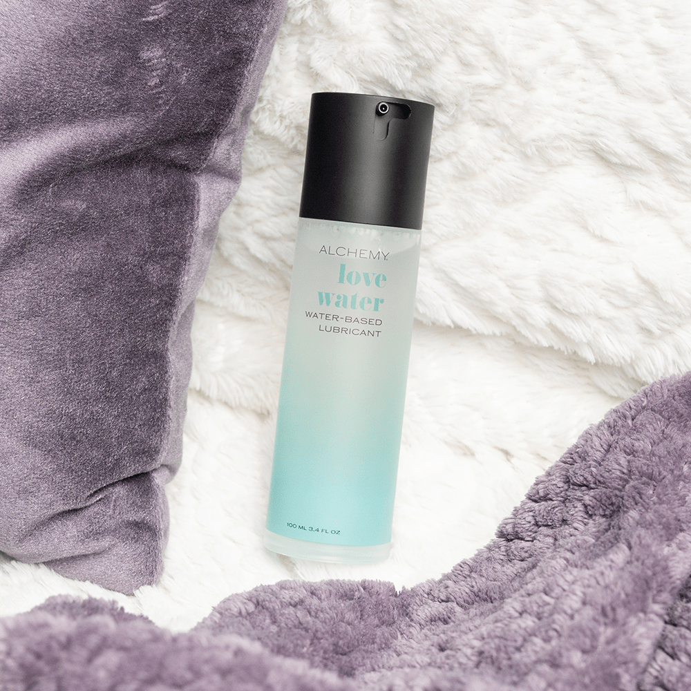 Alchemy Love Water: Water-Based Personal Lubricant bottle on bed blanket