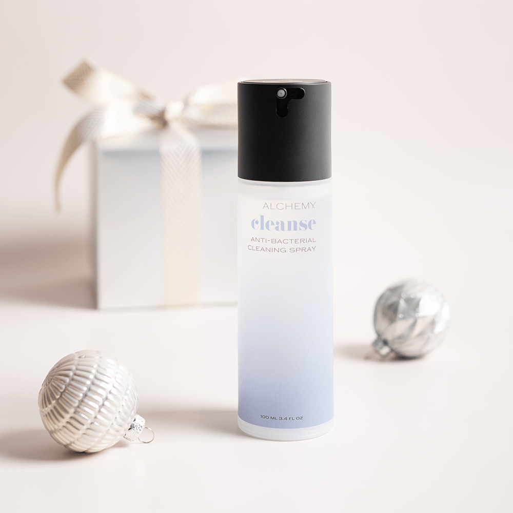 Alchemy Cleanse Antibacterial Toy Cleaner with holiday gift boxes, ornaments, and light pastel background