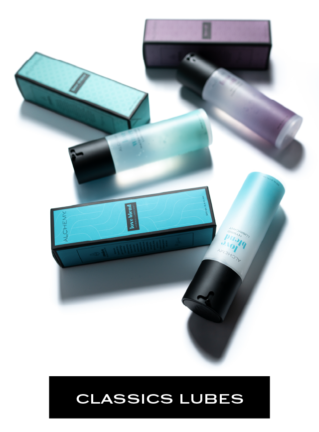 Alchemy Classics Lubes: Photo of bottles of luxury personal lubricant and their boxes on a white studio background. Love Water: Water-Based. Love Oil: Silicone-Based. Love Blend: Hybrid Lube.