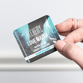 Alchemy Love Water Water-Based Snap + Slide Single-Use Personal Lubricant Packets – close-up of woman's fingers holding packet