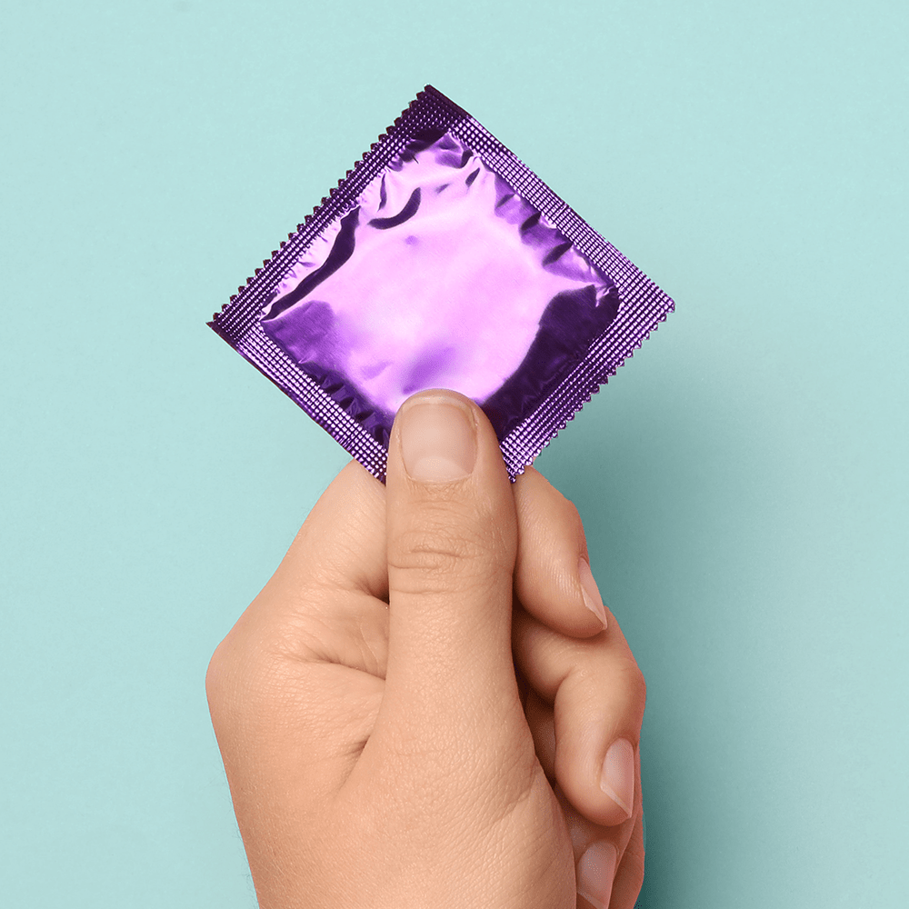 Alchemy Love Water: Water-Based Personal Lubricant – person's  hand holding condom with purple wrapper