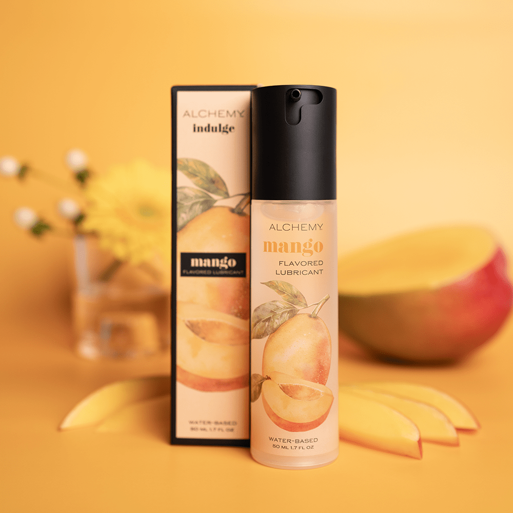 Alchemy Indulge: Mango Flavored Personal Lubricant bottle and box with mango and orange background