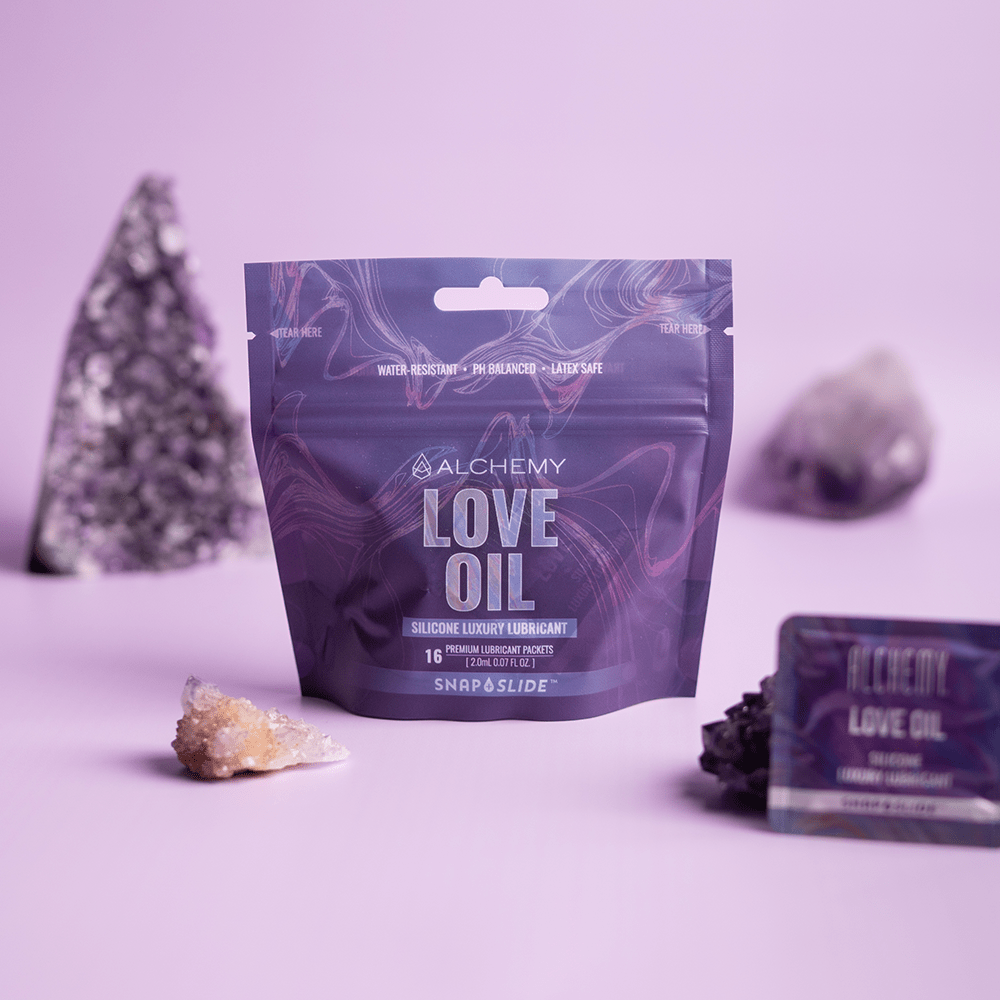 Alchemy Love Oil Silicone-Based Snap + Slide Single-Use Personal Lubricant Packets packaging with crystals