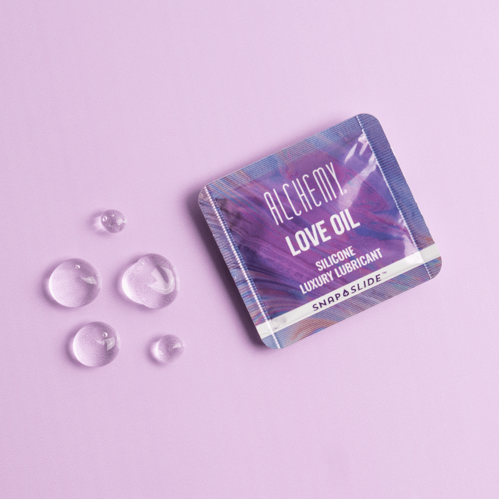 Alchemy Love Oil Silicone-Based Snap + Slide Single-Use Personal Lubricant Packets with liquid droplets