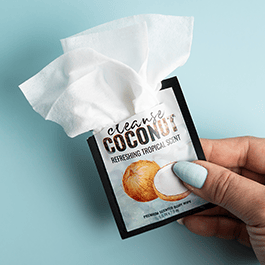 Alchemy Cleanse Coconut Scented Wipes – woman's hand holding single packet, ripped open with wipe peeking out