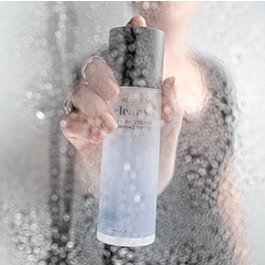 Alchemy Cleanse Antibacterial Toy Cleaner – woman's hand holding Cleanse bottle with droplets on clear surface