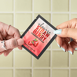 Alchemy Cleanse Strawberry Scented Wipes – woman's hands holding a single packet in front of a tile background