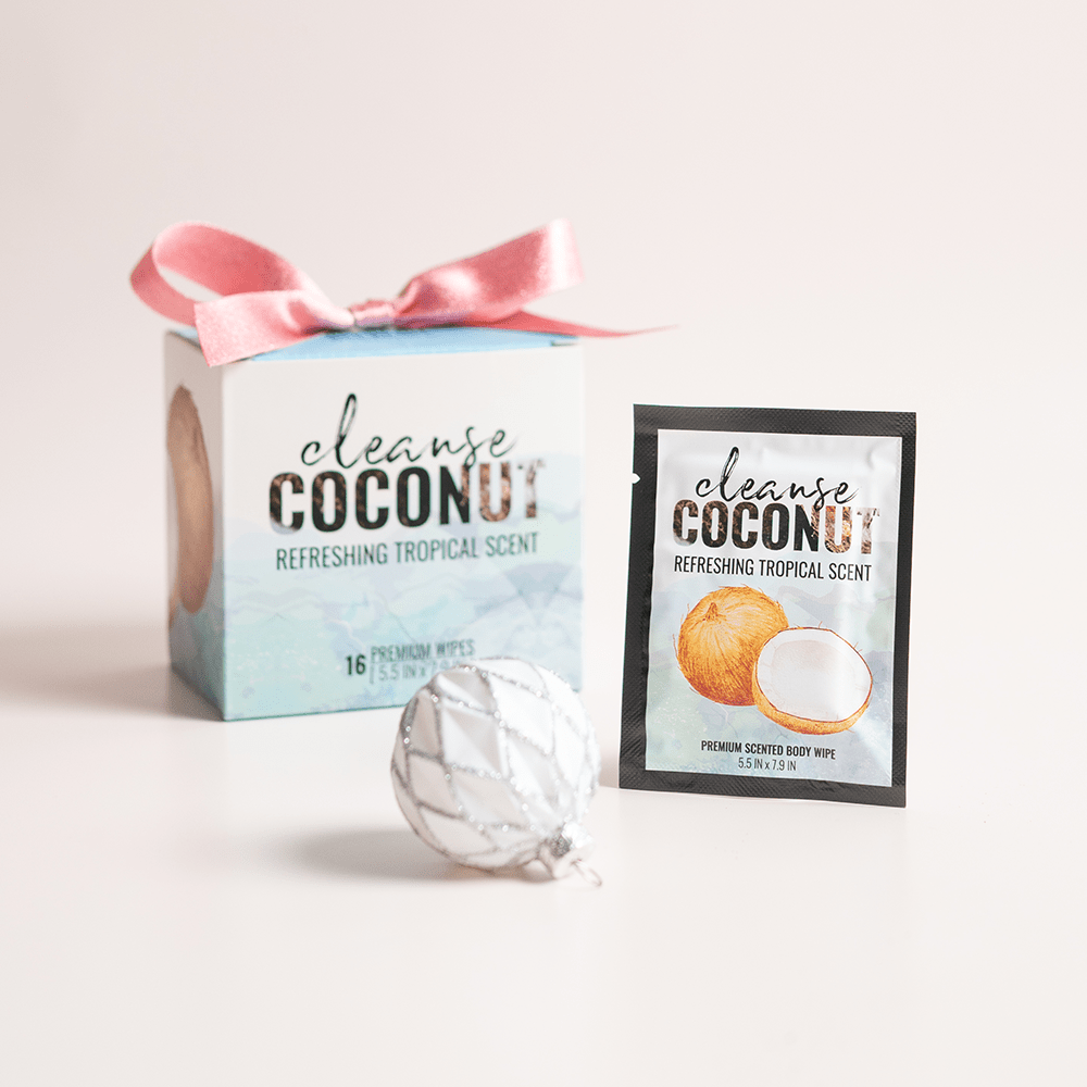 Alchemy Cleanse Coconut Scented Wipes with holiday gift boxes, ornaments, and light pastel background