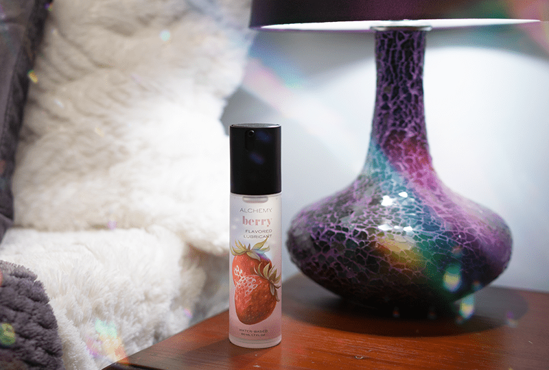 Alchemy Indulge: Strawberry Flavored Personal Lubricant bottle on nightstand