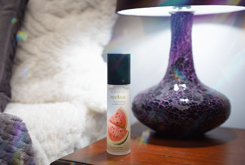 Alchemy Indulge: Watermelon Flavored Personal Lubricant bottle on nightstand