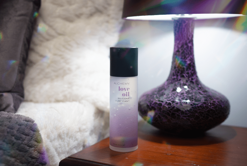 Alchemy Love Oil: Silicone-Based Personal Lubricant bottle on nightstand