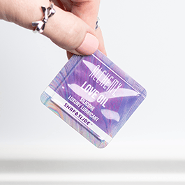 Alchemy Love Oil Silicone-Based Snap + Slide Single-Use Personal Lubricant Packets – close-up of woman's fingers holding packet
