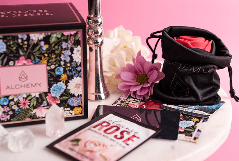 Alchemy Rosebud: Luxury Air-Pulse Massager with box and included accessories on a marble