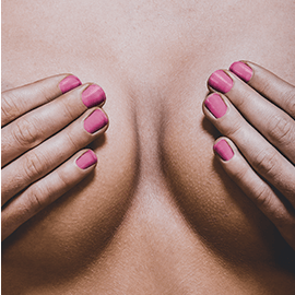 Photo of a woman's hands covering her breasts with contrasty lighting