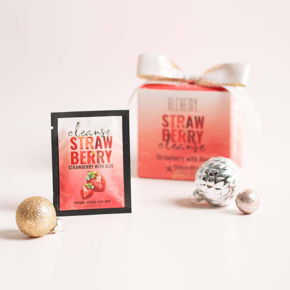 Alchemy Cleanse Strawberry Scented Wipes with holiday gift boxes, ornaments, and light pastel background