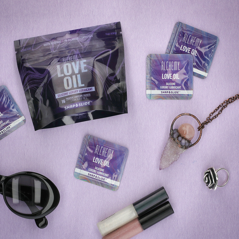Love Oil Snap + Slide™ Multiple Packs with Bag next to jewelry and lip balm